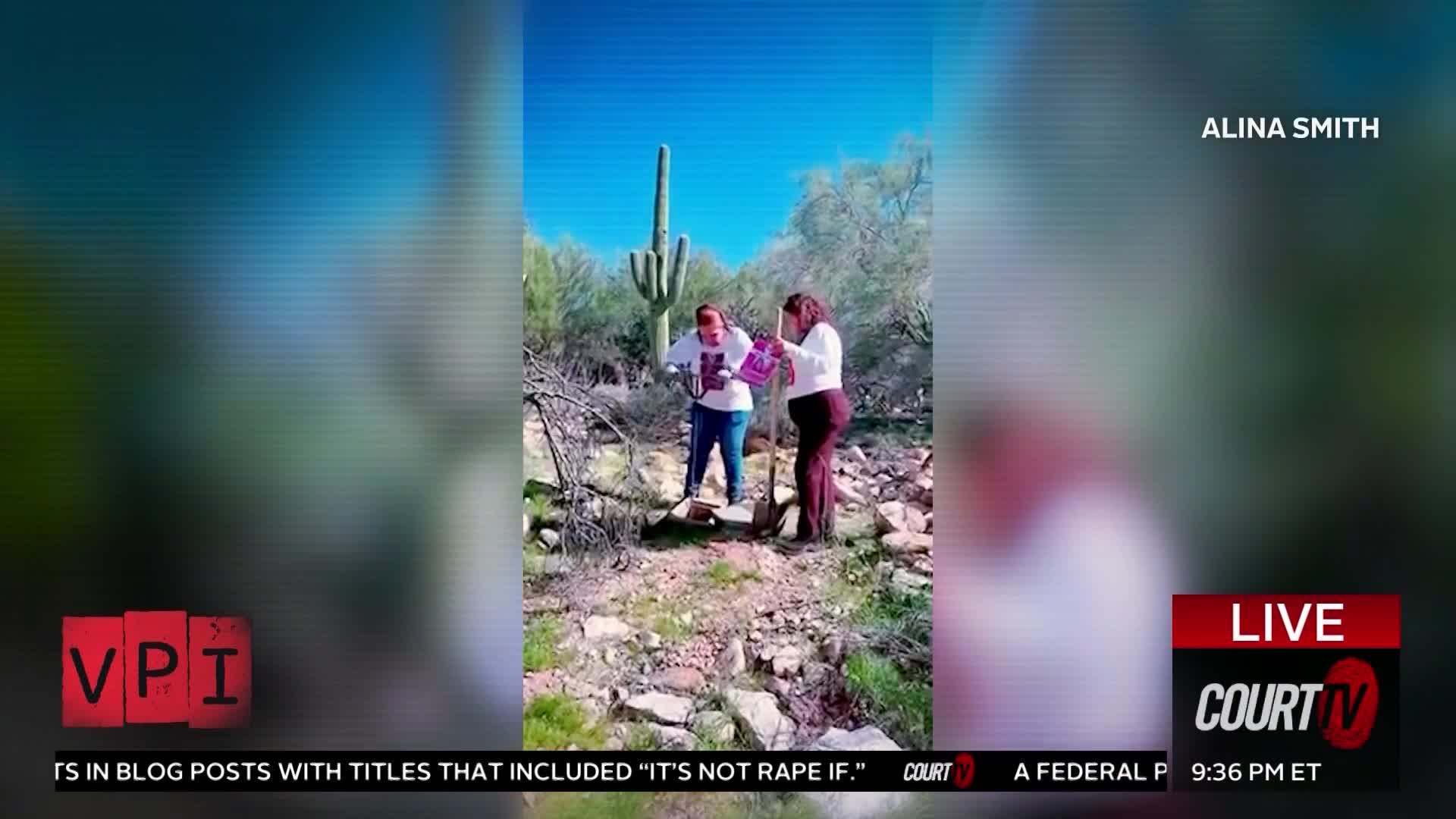 Two women stand in a dry, rocky landscape with a tall saguaro cactus behind them. One woman holds a shovel, and the other clutches a purple bag.