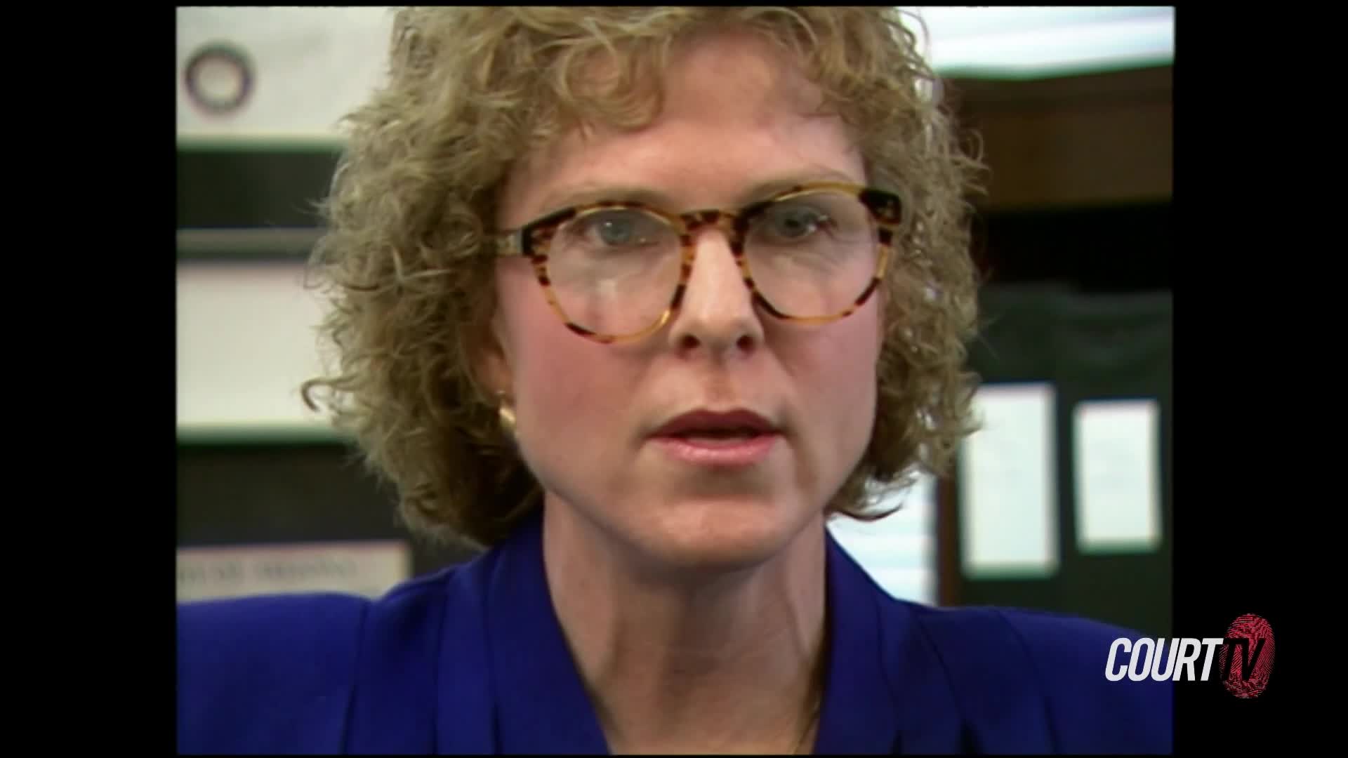 A woman with curly hair and large, patterned glasses speaks directly to the camera. She wears a royal blue jacket, and the Court TV logo appears in the lower right corner.