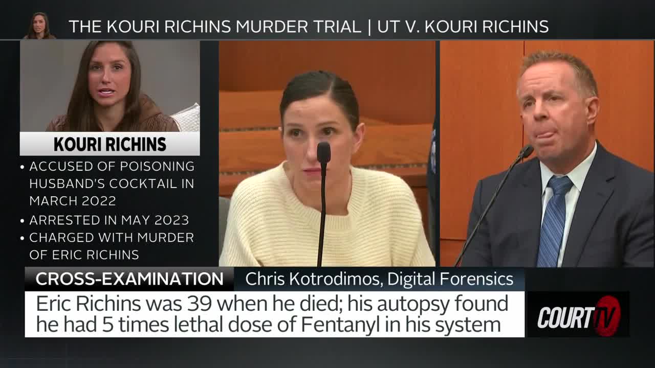 A woman sits at a table, her gaze fixed forward as a man in a suit speaks into a microphone. Court TV's broadcast of the Kouri Richins murder trial displays details about the charges.