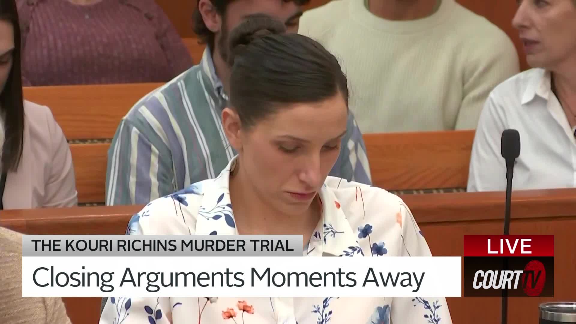 The Kouri Richins murder trial is about to begin its closing arguments. A woman in a floral shirt looks down, her expression unreadable.