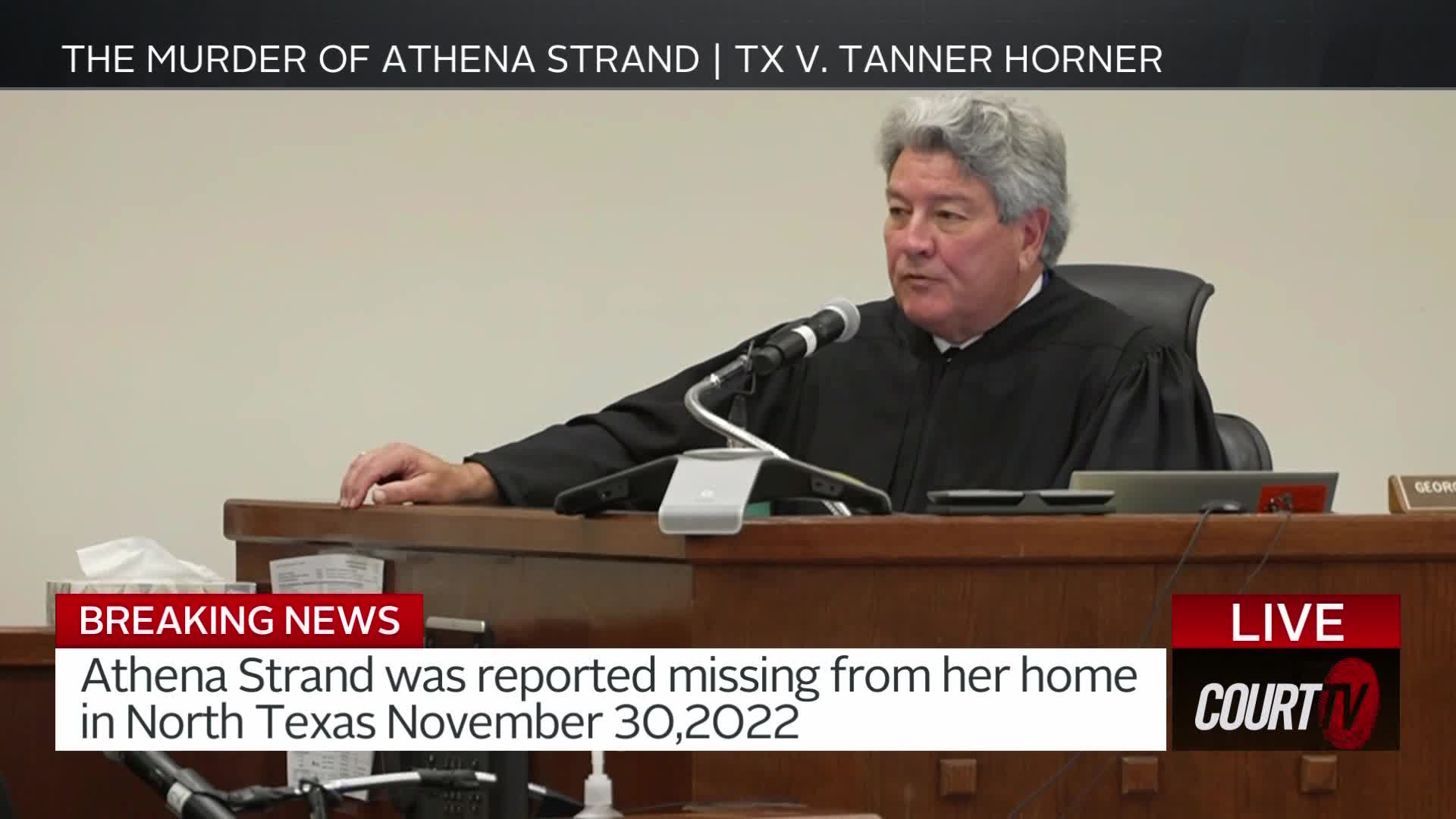 A judge in a black robe sits behind a wooden bench, speaking into a microphone. A breaking news banner across the bottom of the screen states Athena Strand was reported missing from her North Texas home on November 30, 2022.