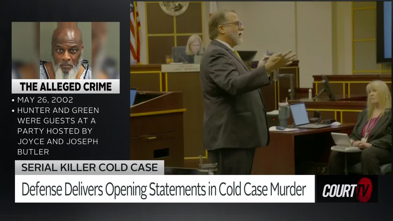 A defense attorney gestures emphatically as he speaks to the jury. A woman in a pink shirt sits attentively at a table, listening intently.