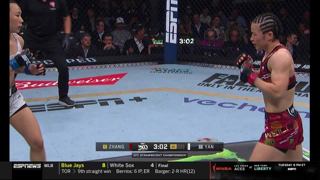 Zhang and Yan stand poised in the octagon, gloves up, ready to engage. The clock on ESPNews shows 3:02 in the round.
