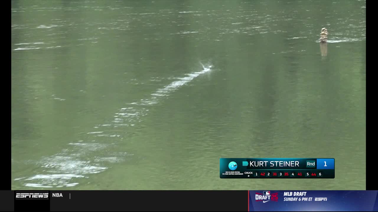 A wake of white foam stretches across the water, leading to a small boat in the distance. The ESPNews graphic shows Kurt Steiner in Round 1.
