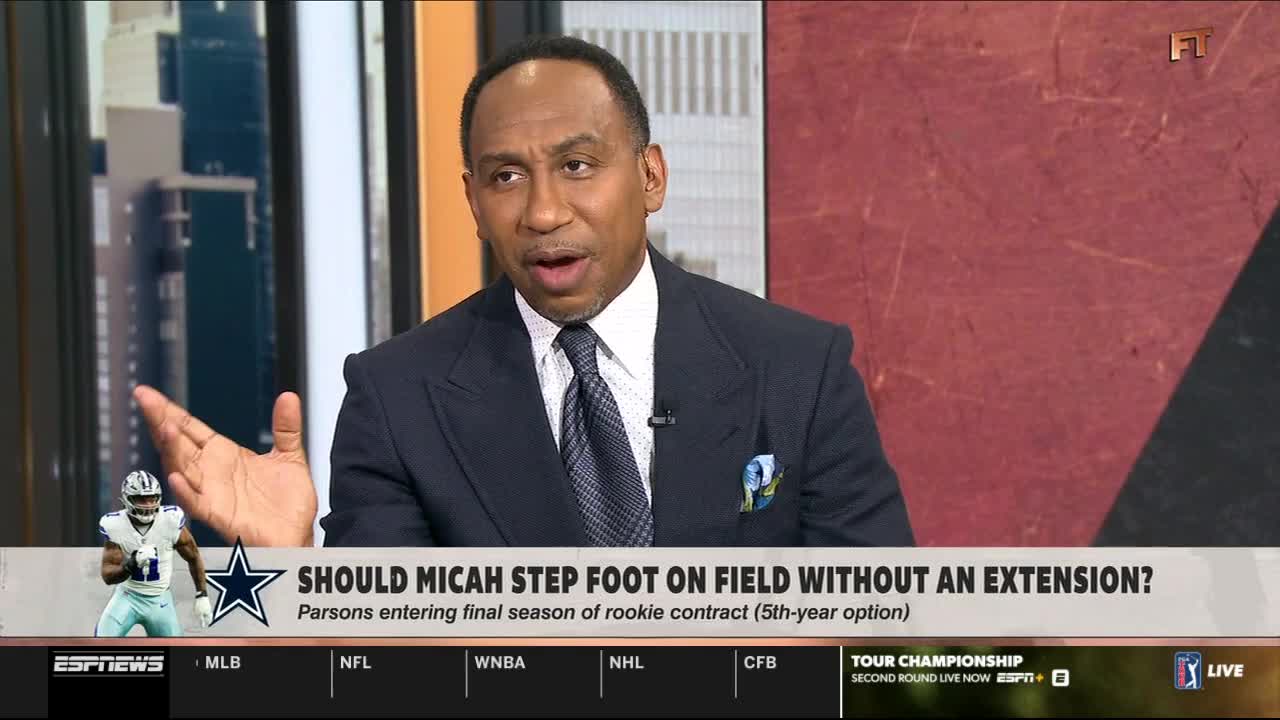 A man in a suit gestures emphatically while discussing a football player's contract on ESPNews. The screen displays the question of whether Micah Parsons should play without an extension.
