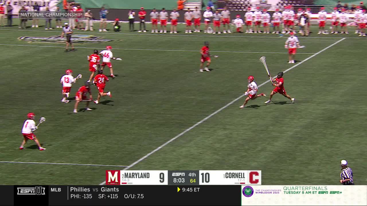 A player in red sprints toward the goal, stick raised, as another player in white chases him. The score is close, and the clock is ticking down in the fourth quarter.
