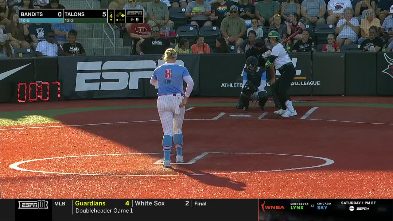 The pitcher, wearing number 8, walks off the mound as the batter prepares to swing. The catcher is crouched, ready for the pitch, as the scoreboard shows the score on ESPNU.
