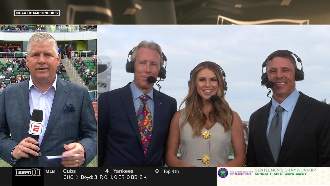 Three people in suits with headsets stand in front of a camera, smiling, while a man on the left holds a microphone with an "E" logo. The background shows a stadium and the ESPNU logo, with a banner for the Wimbledon Gentlemen's Championship.
