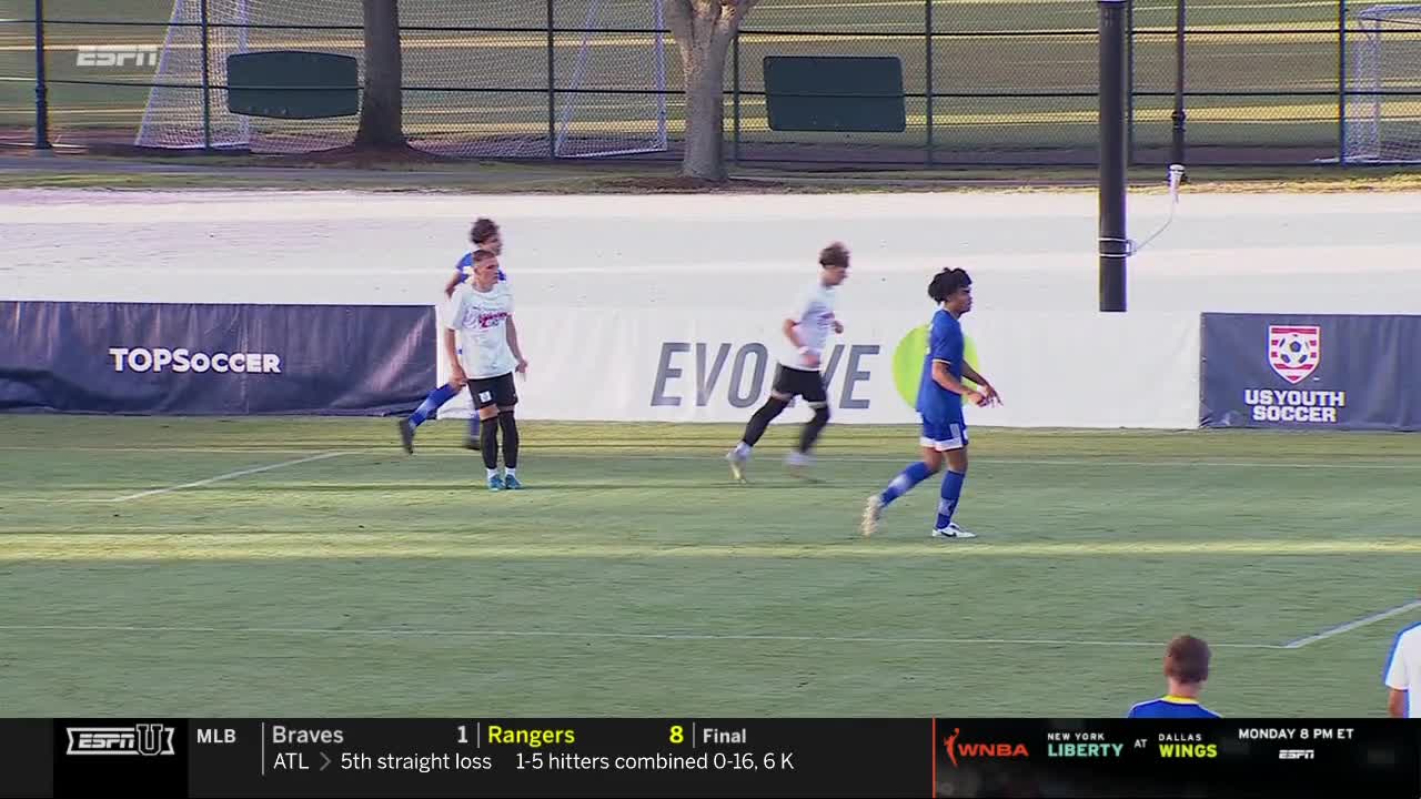 A player in blue sprints toward the right side of the field, while others in white and blue jerseys are scattered across the green turf. The ESPNU logo is visible in the corner, indicating a broadcast of the match.
