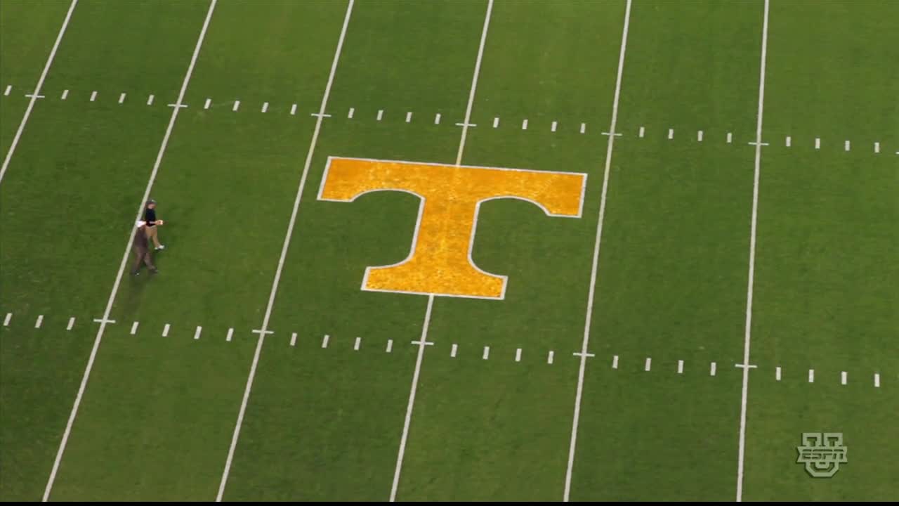 Two people walk across the green field, heading toward the large orange "T" at midfield. The ESPNU logo is visible in the corner.
