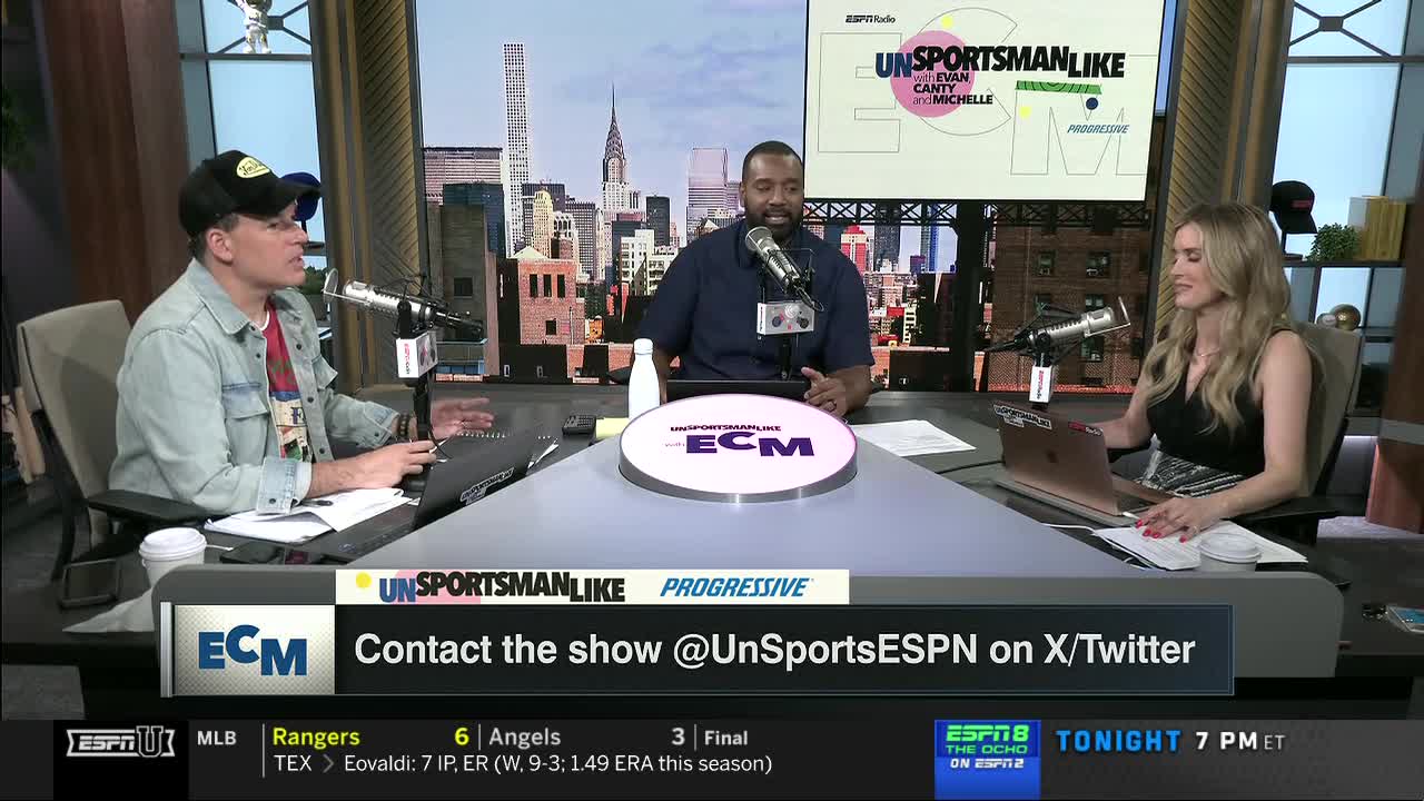 Three people are seated at a desk, each with a microphone, in front of a cityscape backdrop. The show, "Unsportsmanlike," is being broadcast on ESPNU.
