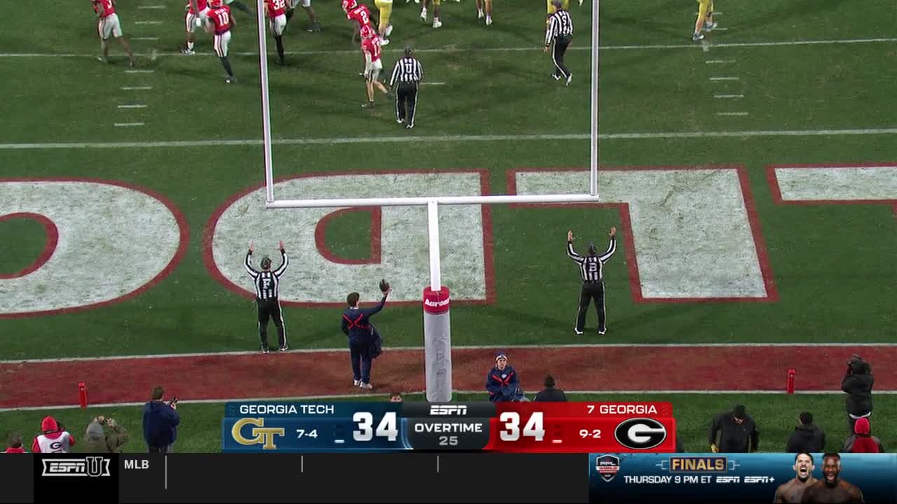 The referees signal a good score as the teams are tied in overtime. The scoreboard on ESPNU shows Georgia Tech and Georgia with identical scores.
