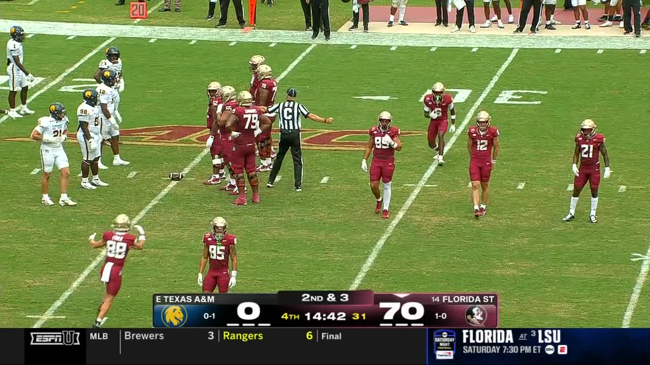 The referee signals a penalty as the Florida State players in maroon jerseys gather. Several players walk away from the group, while the scoreboard shows a significant lead for Florida State.
