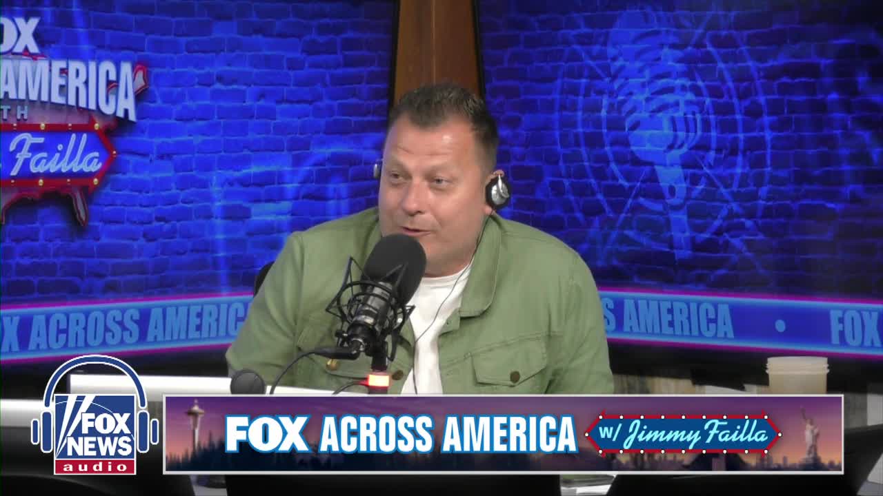 Jimmy Failla, from Fox News Radio, speaks into a microphone, wearing a headset and a green jacket. Behind him, the set features a blue brick wall and the "Fox Across America" logo.
