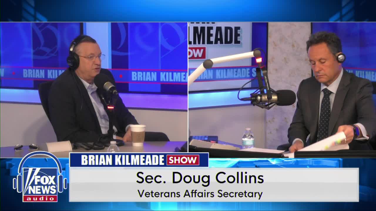 Doug Collins, Veterans Affairs Secretary, speaks into a microphone. Beside him, Brian Kilmeade flips through papers.