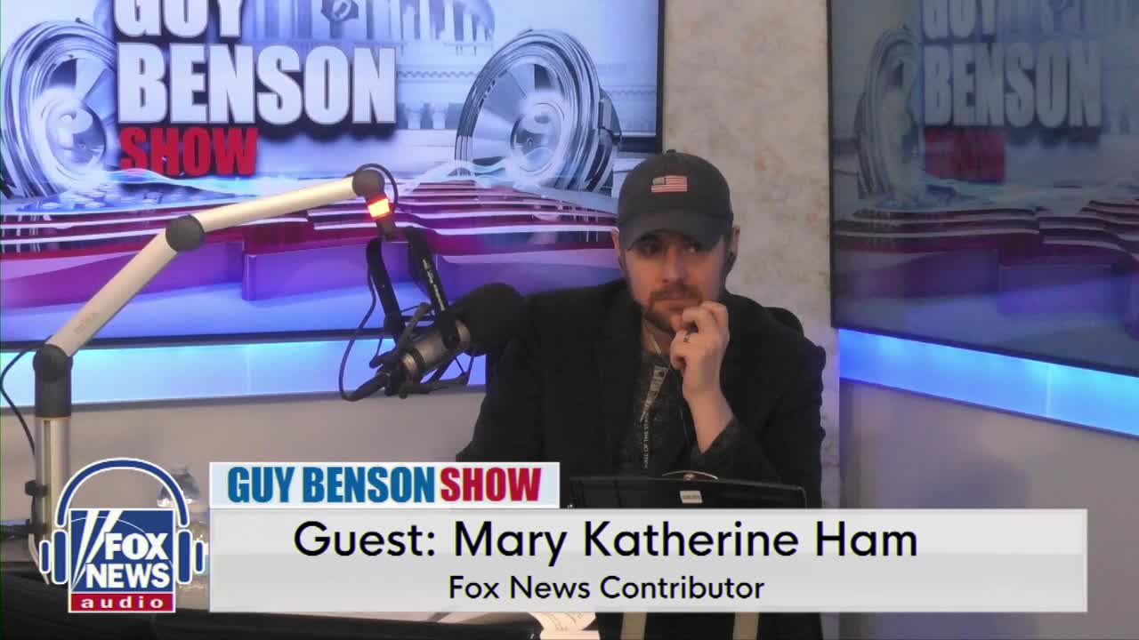 A man in a baseball cap leans forward, hand to his chin, in front of a microphone. The "Guy Benson Show" logo and "Guest: Mary Katherine Ham" are displayed on screen.