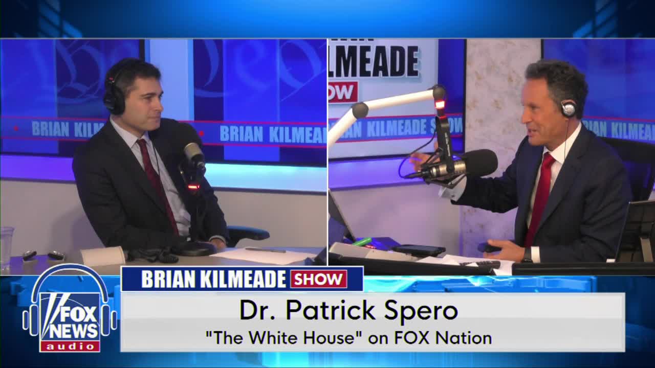 Two men in suits sit at desks, each with a microphone in front of them. The man on the right, wearing headphones, gestures with his hand as he speaks into the mic. A graphic identifies them as Dr. Patrick Spero and the Brian Kilmeade Show on Fox News Radio.