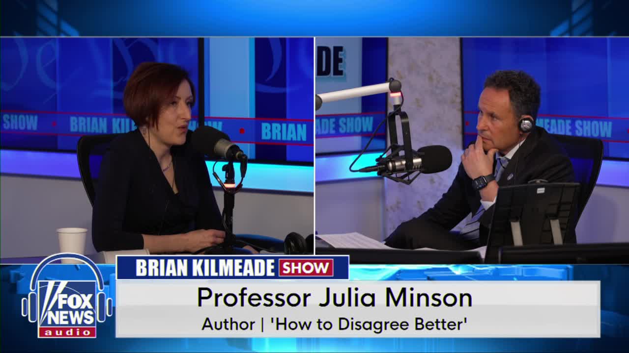 A woman with short, dark hair speaks into a microphone, her left hand resting on the table. Across from her, a man in a suit and tie listens intently, his chin propped on his hand. The Fox News Audio logo is visible at the bottom left.