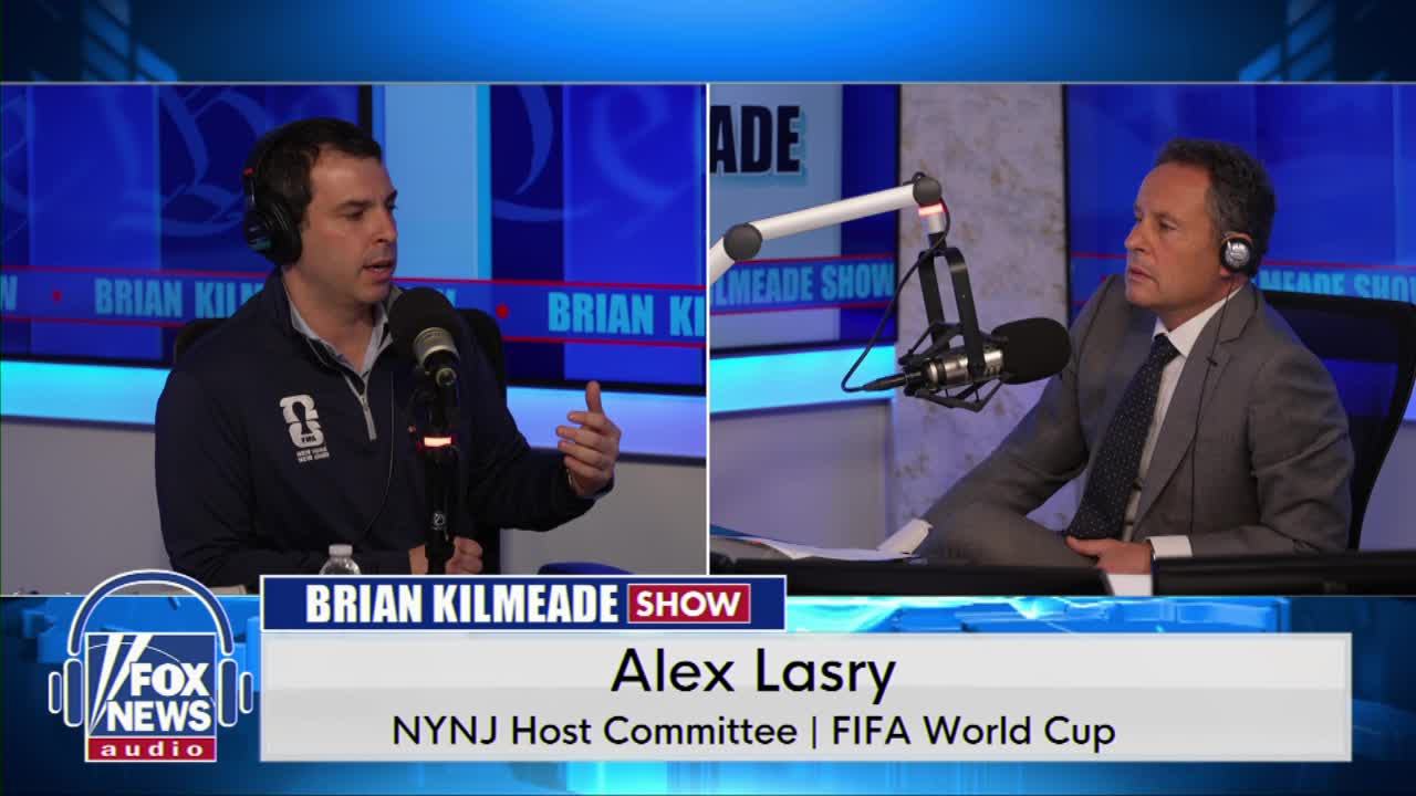 A man in a blue jacket gestures with his right hand while speaking into a microphone. Across from him, a man in a gray suit leans forward, listening intently. The "Brian Kilmeade Show" graphic appears on screen.