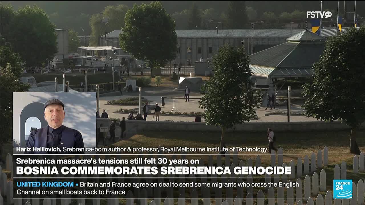 A man in a hat speaks on a screen, while in the background, people walk around a memorial site. The Free Speech TV logo is visible, and the news is about the Srebrenica genocide.
