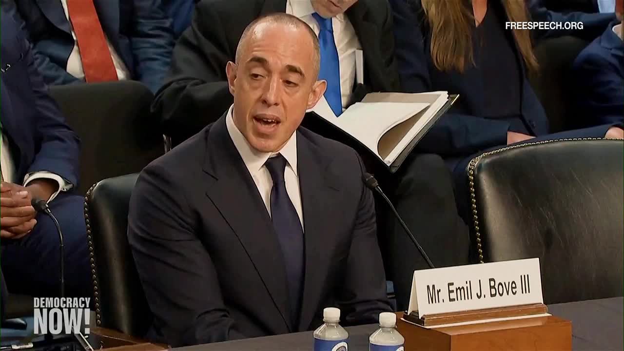 A man in a dark suit speaks into a microphone, his mouth open as he addresses the committee. His name, Emil J. Bove III, is on a small sign in front of him, and Free Speech TV is broadcasting.
