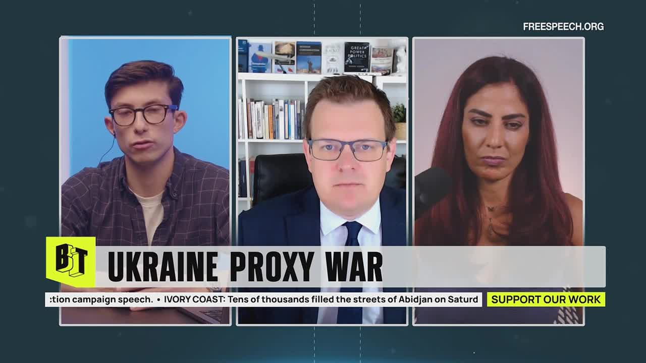 Three people, each in their own frame, are positioned across the screen, all wearing headsets. Below them, the words "UKRAINE PROXY WAR" are displayed on the screen, with the Free Speech TV logo in the corner.
