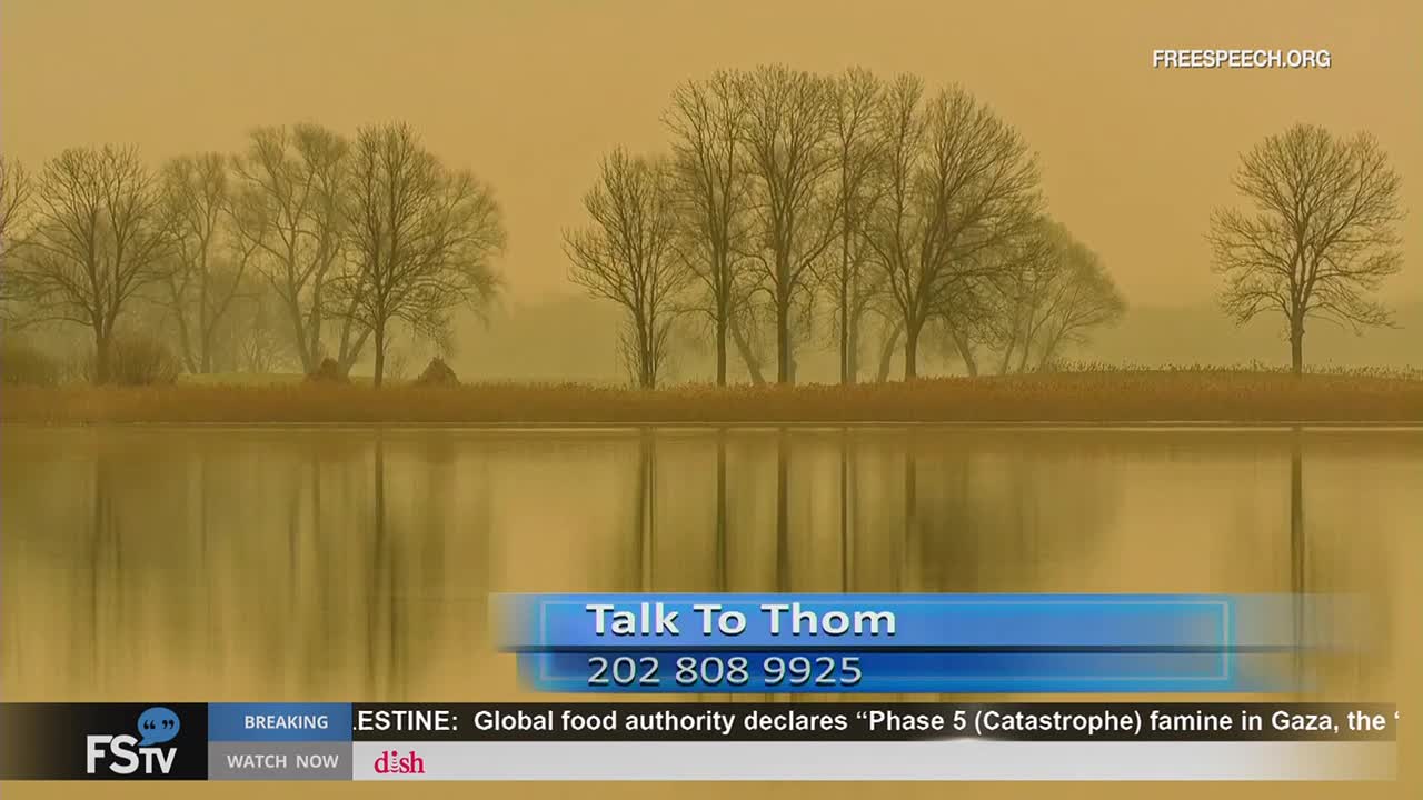 A tranquil lake reflects the bare trees along the far bank. The image is a backdrop for a segment on Free Speech TV, with a phone number displayed at the bottom.
