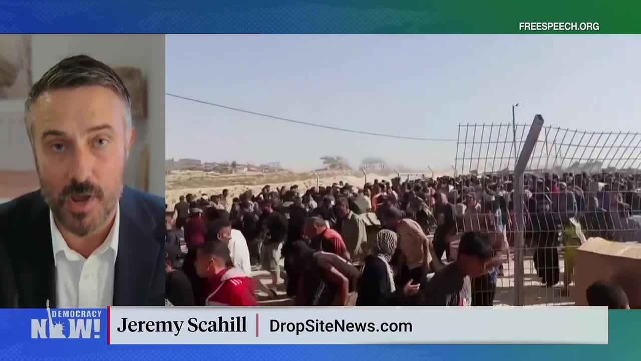 A large crowd of people presses against a metal fence, some reaching out. Across the screen, a man on Free Speech TV in the United States speaks, reporting on the scene.
