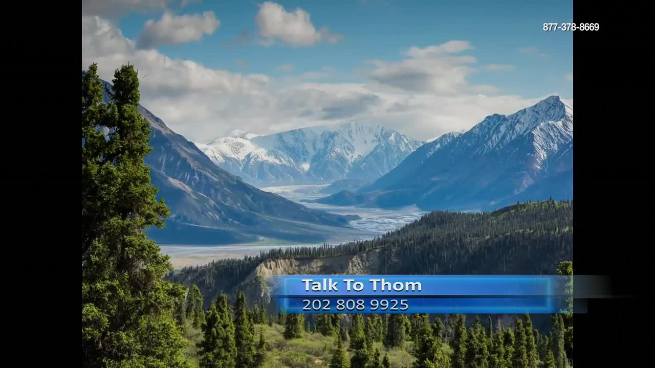 A wide valley stretches toward snow-capped mountains under a bright blue sky. A graphic at the bottom of the screen identifies a program called "Talk to Thom" on Free Speech TV.
