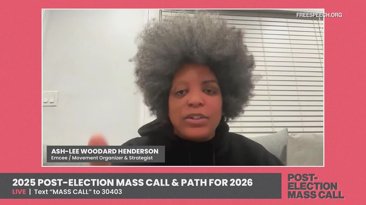 Ash-Lee Woodard Henderson is speaking directly into the camera on Free Speech TV. Her hair is a cloud of gray, and the text at the bottom invites viewers to text for a "Mass Call."
