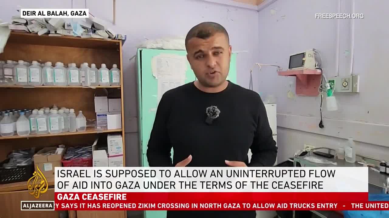 A man in a black shirt stands in what looks like a medical facility, speaking directly to the camera. The Free Speech TV logo is visible, and text on the screen discusses aid to Gaza.
