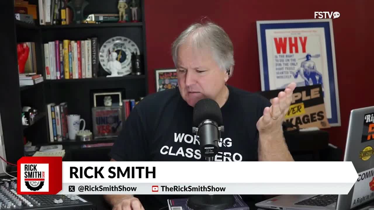 Rick Smith, on Free Speech TV, gestures with his right hand as he speaks into a microphone. His show's name and social media handles are displayed below him.
