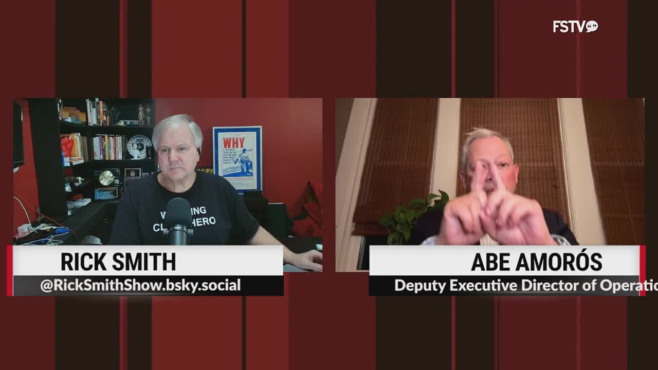 Rick Smith, wearing a t-shirt that reads "Working Class Hero," sits in front of a bookshelf. Abe Amorós, identified as Deputy Executive Director of Operations, holds his fingers up in front of his face.