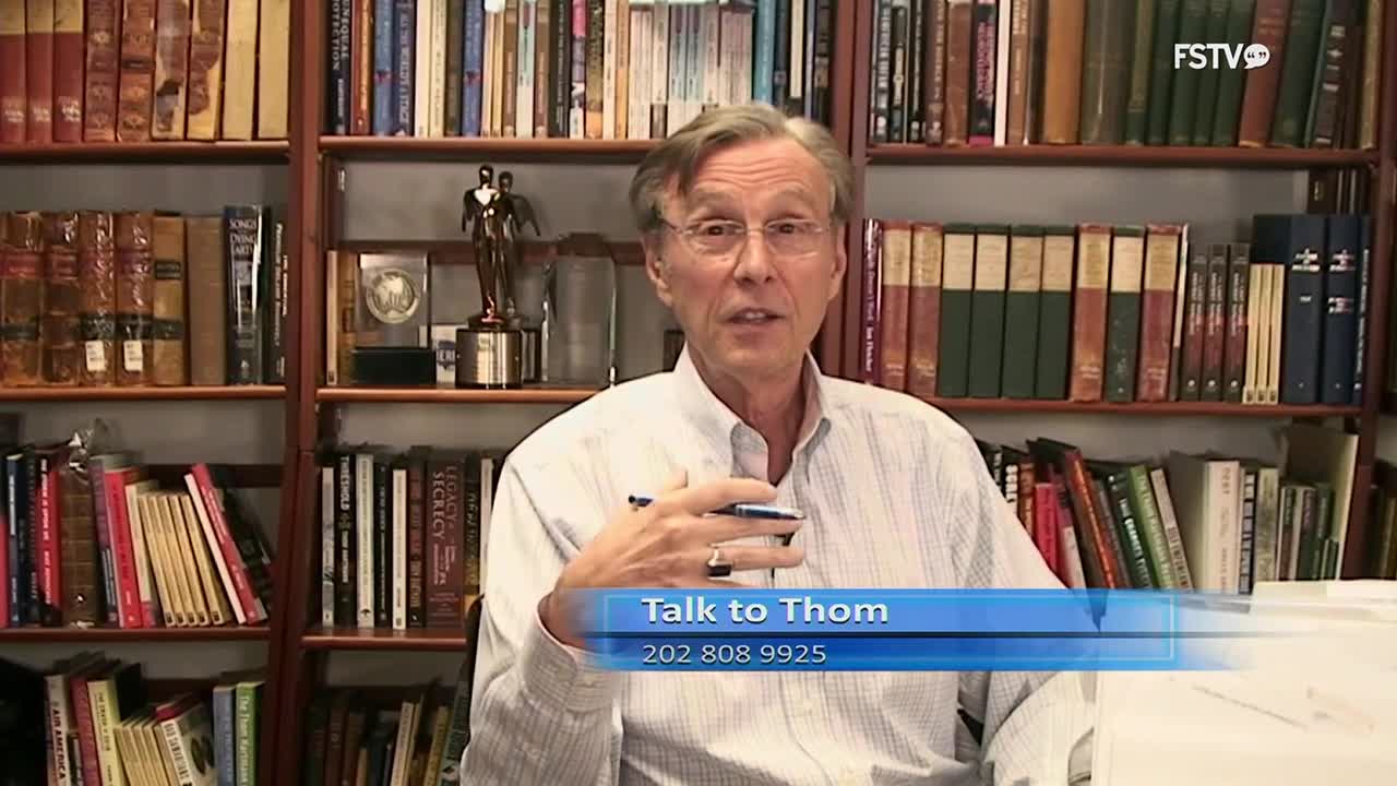 A man in a collared shirt speaks directly to the camera, gesturing with a pen. Behind him, bookshelves overflow with volumes, a testament to a life of learning.