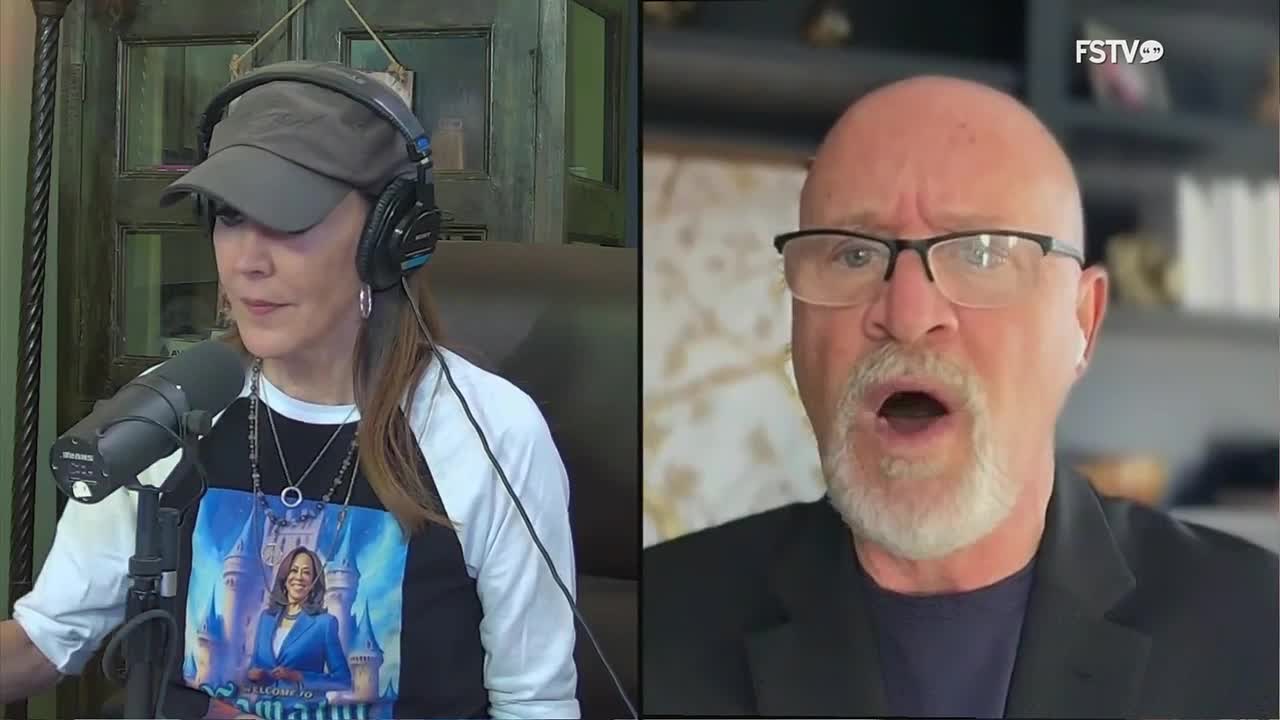 A man with glasses and a white beard speaks with his mouth open, his expression animated. Beside him, a woman wearing a baseball cap and headphones looks down, a microphone positioned in front of her.