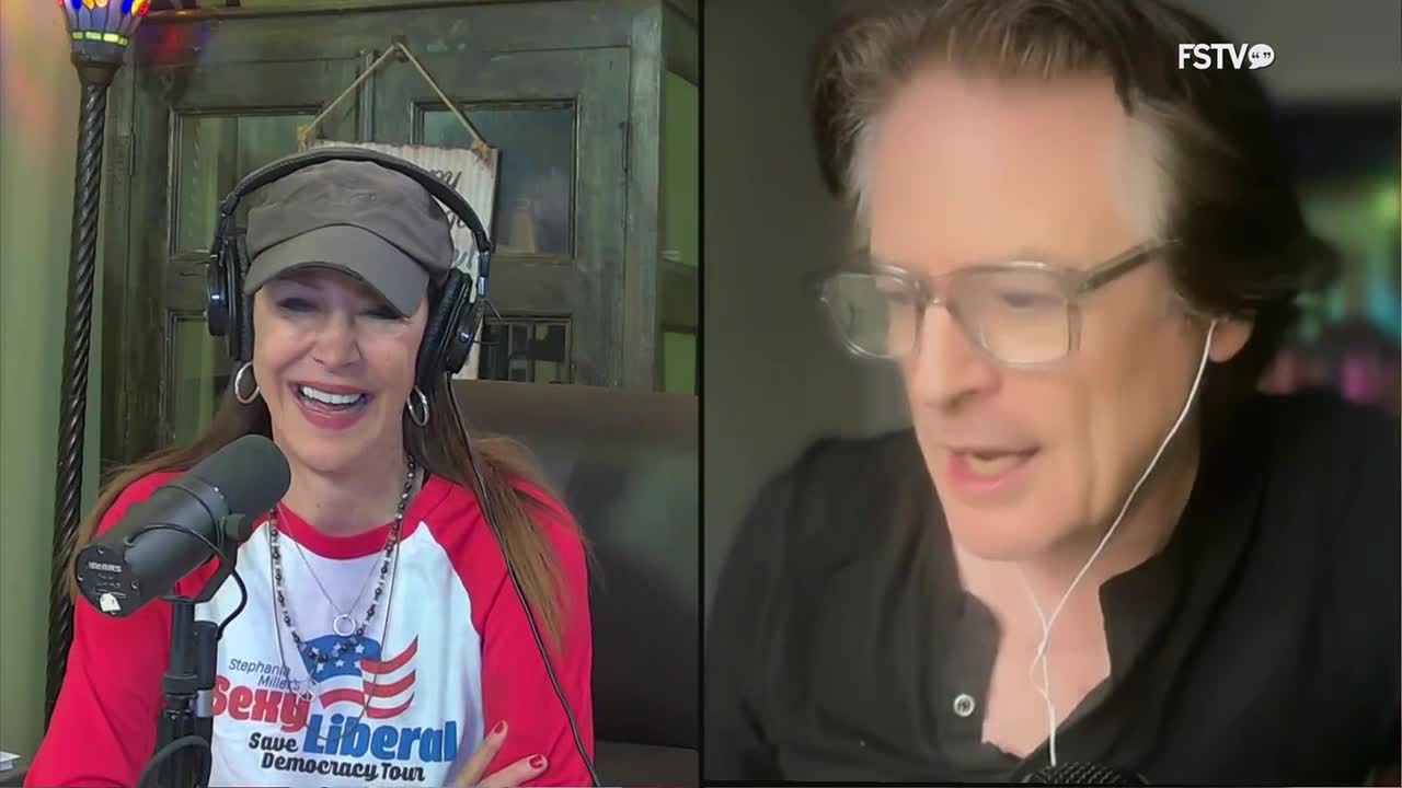A woman in a baseball cap and a red and white shirt laughs into a microphone, while a man with glasses speaks into his own. The Free Speech TV logo appears in the corner of the screen.