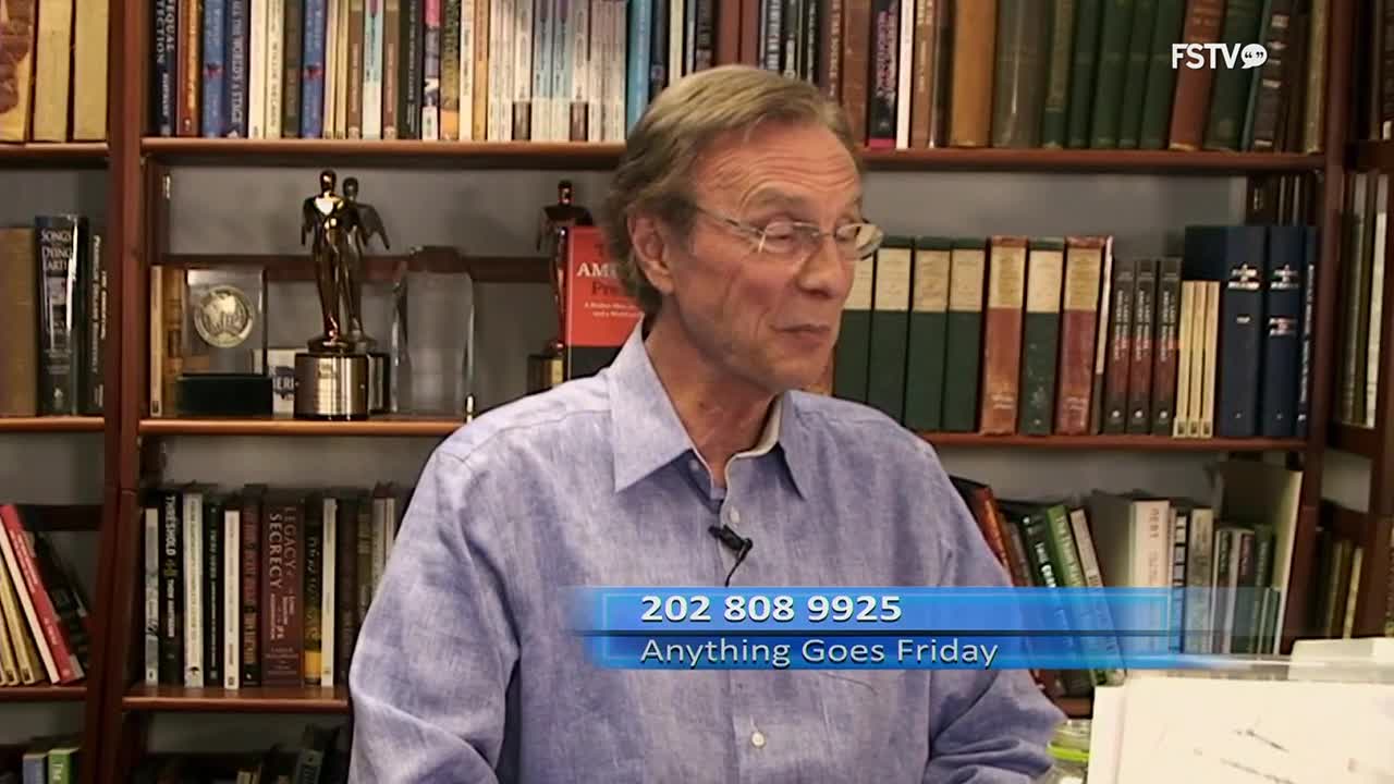 A man with glasses, wearing a blue button-down shirt, speaks in front of bookshelves. A graphic overlay displays "202 808 9925" and "Anything Goes Friday."