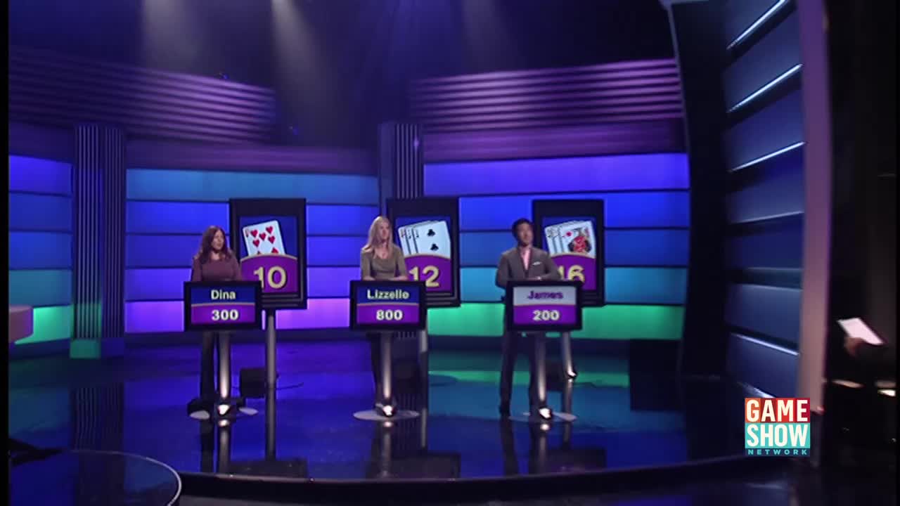 Three contestants stand at podiums, each facing a large card display on this Game Show Network set. Their scores are visible beneath their names, and the cards indicate the round is in progress.
