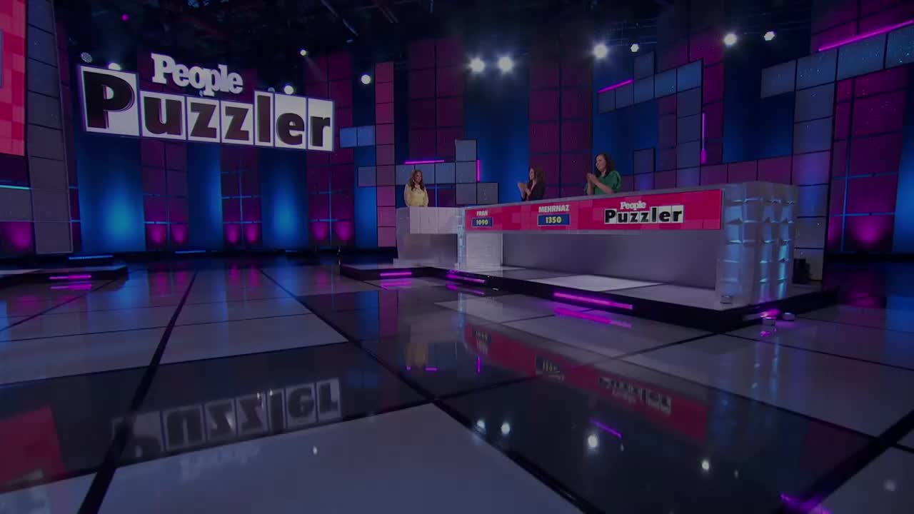 On a brightly lit stage, the set for *People Puzzler* gleams with a checkered floor and a large screen displaying the show's logo. Three women stand behind a desk, applauding, as the game show's host likely introduces the next puzzle.
