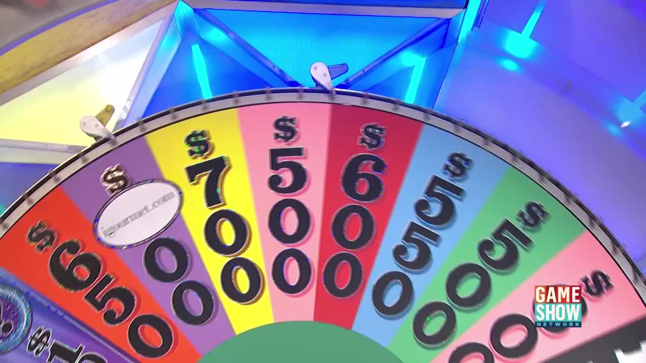 The colorful wheel, with dollar amounts printed on it, is spinning. The white pointer at the top is about to land on a prize amount.
