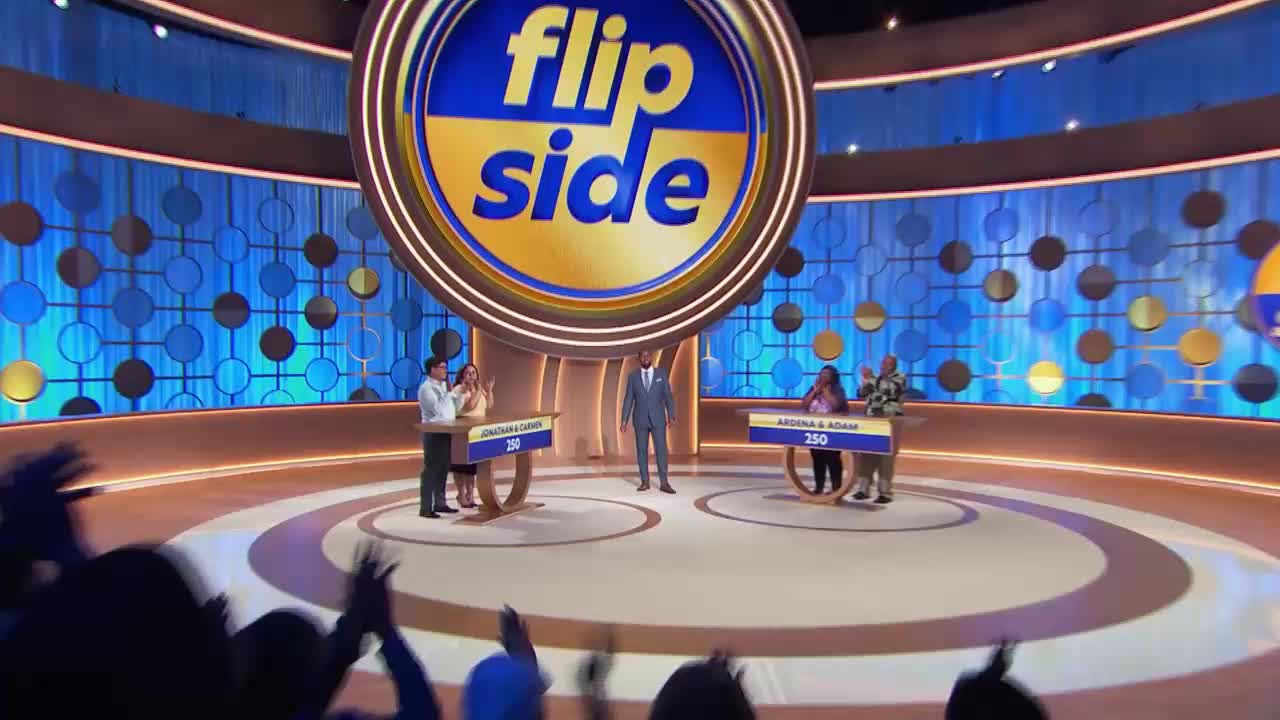 Two teams stand at podiums, each with a score of 250, on the "Flip Side" set. The host, dressed in a suit, stands between them, as the audience applauds.
