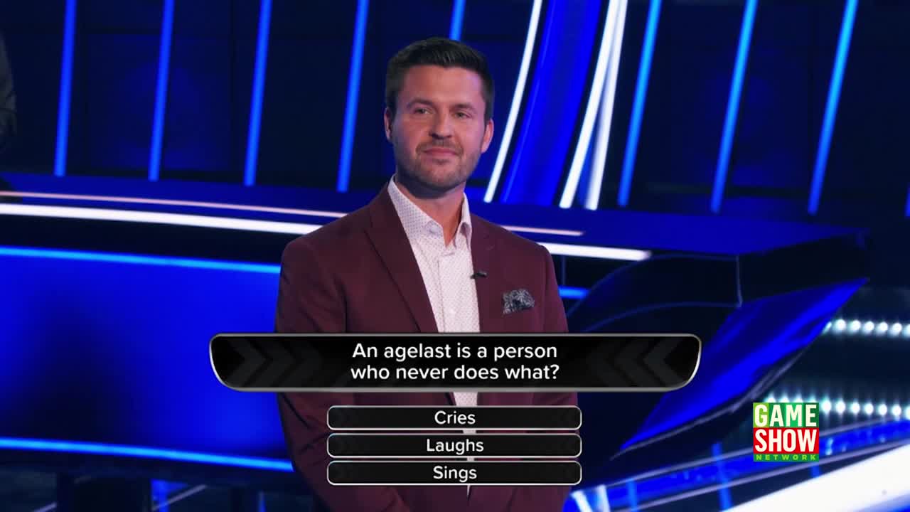 The host, wearing a burgundy suit, looks directly at the camera on the Game Show Network set. A question about an agelast is displayed on the screen below him, with answer choices ready.
