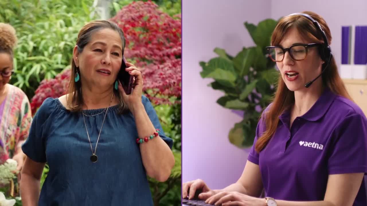 A woman in a blue shirt stands outdoors, talking on her phone. Across from her, a woman in a purple Aetna shirt speaks into a headset while typing.