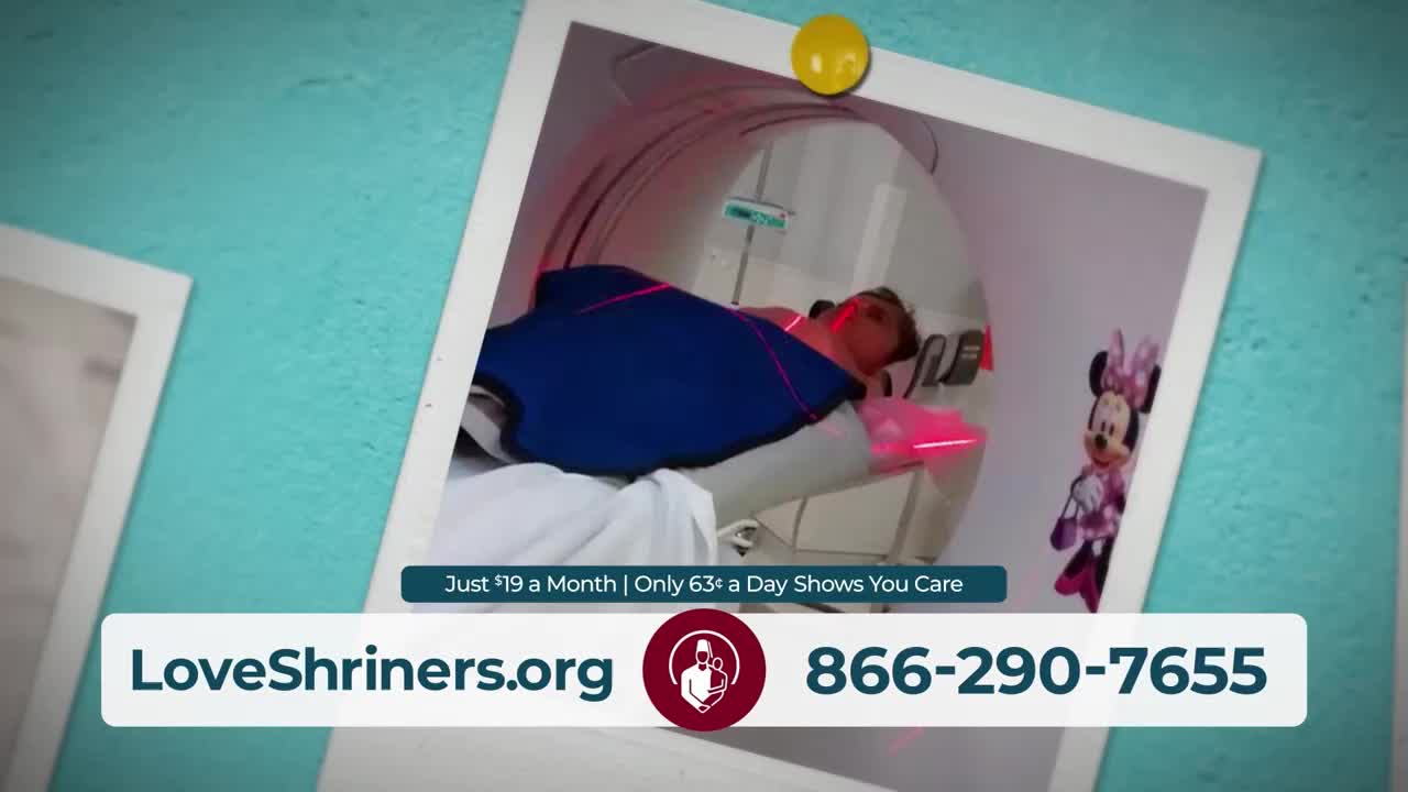 A person lies on a table inside a medical scanner, bathed in red light. A Minnie Mouse toy stands nearby, a cheerful presence in the room.