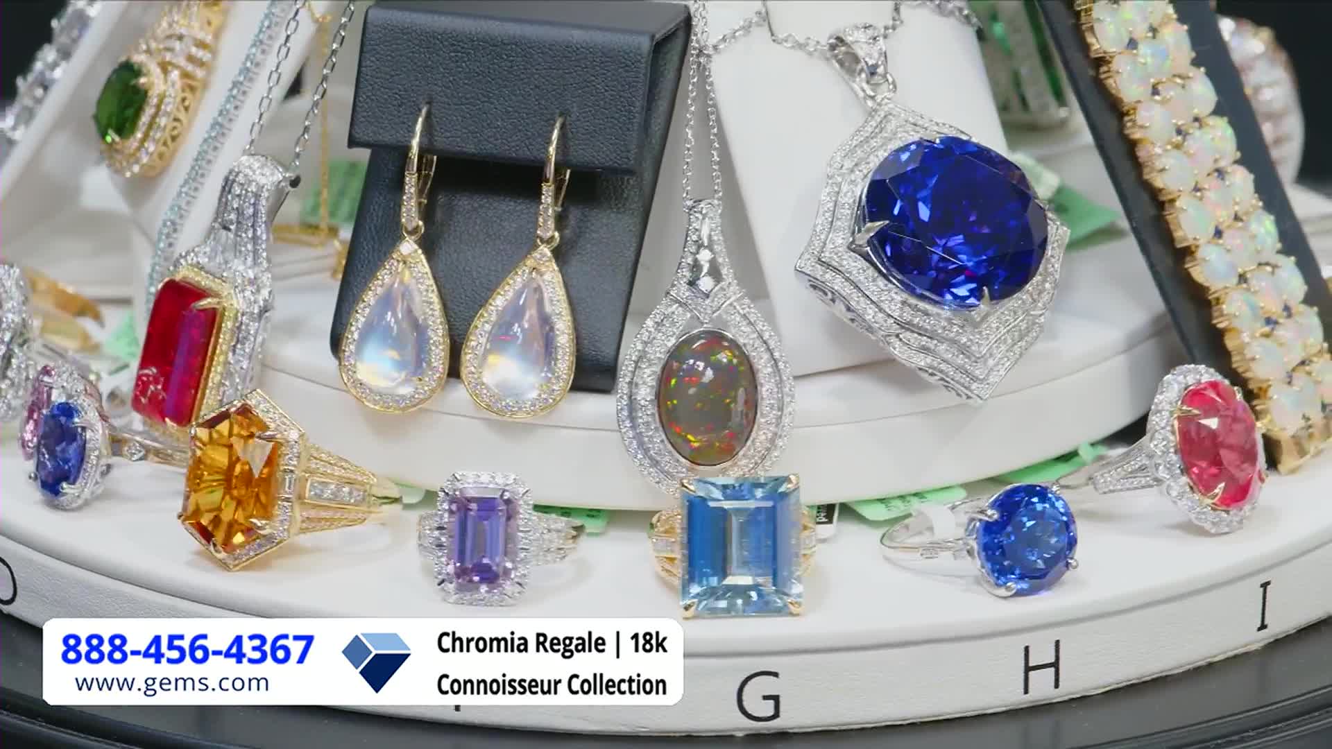 A collection of sparkling rings, earrings, and pendants is arranged on a rotating display, ready for their close-up on the Gem Shopping Network. The camera focuses on the shimmering gemstones, showcasing their vibrant colors and intricate settings.

