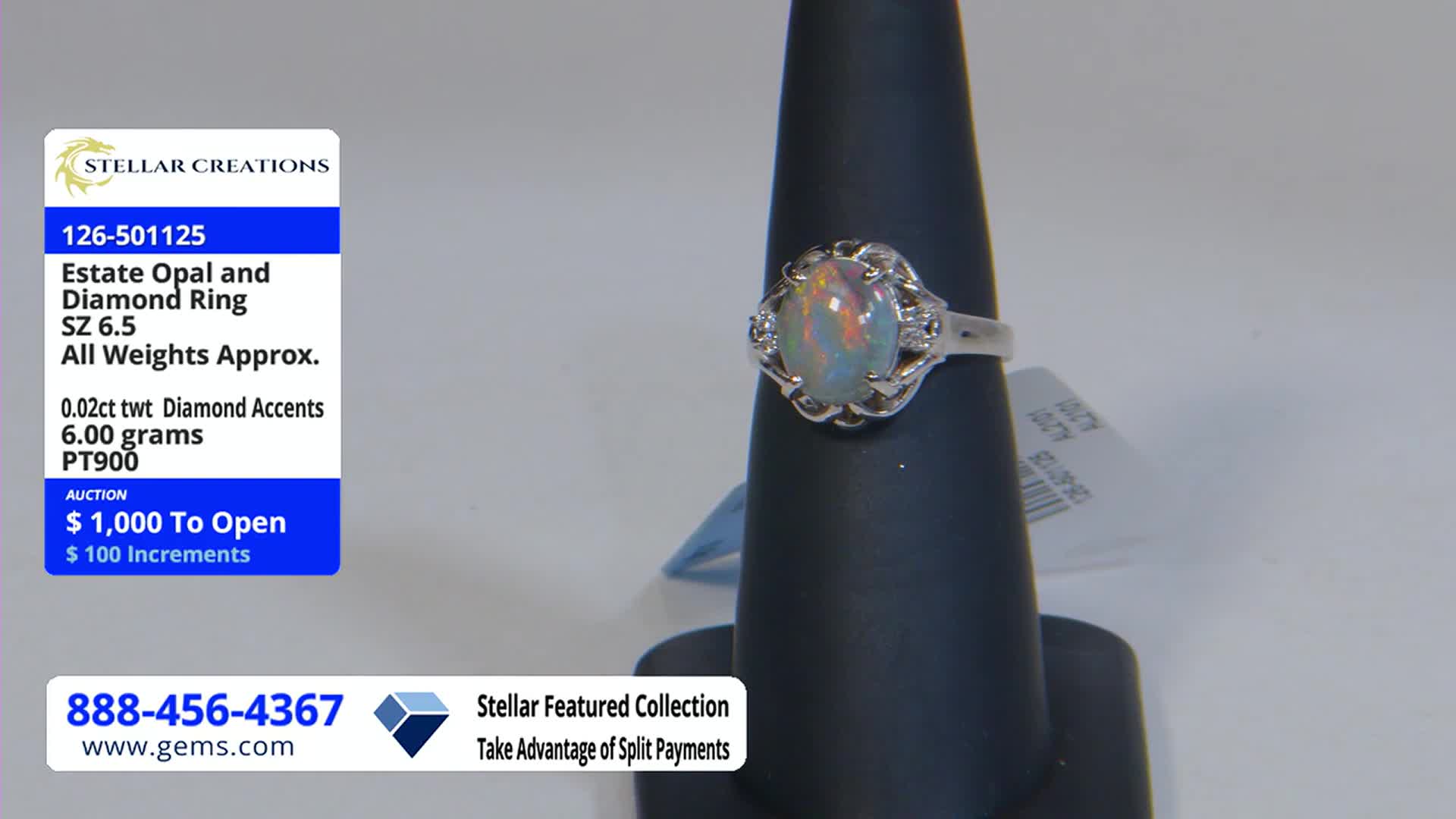 A ring with a large, iridescent opal sits on a black display stand. The Gem Shopping Network is advertising the ring's auction, starting at $1,000.
