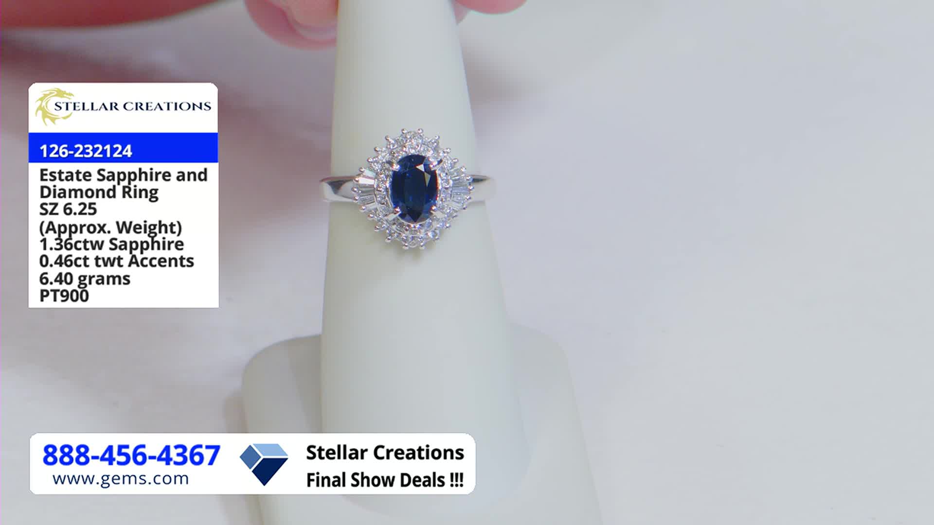 A hand holds a platinum ring with a dark blue oval sapphire, surrounded by diamonds, centered on a white display. The Gem Shopping Network logo and details about the ring are shown in the corner.
