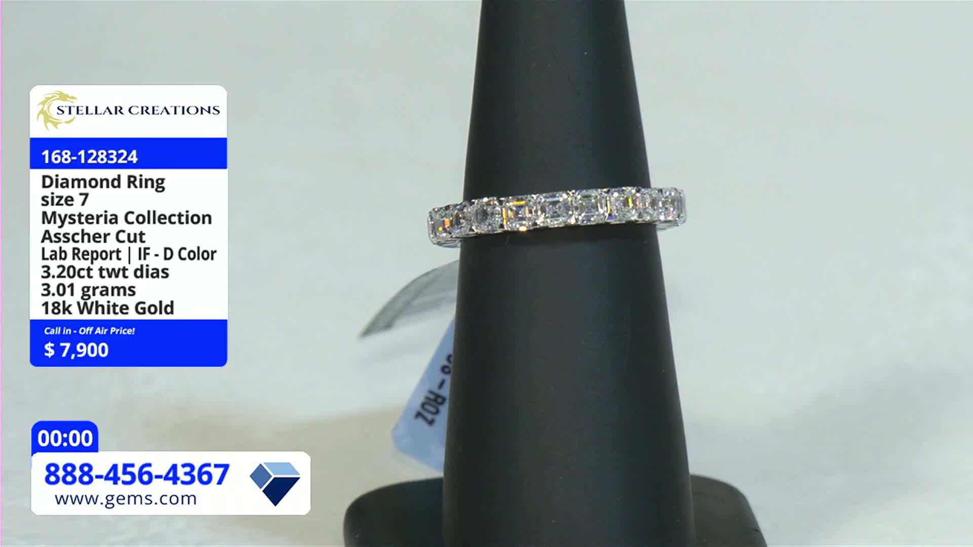 A diamond ring, set with square-cut stones, sits on a black display stand. The Gem Shopping Network logo and price tag are visible in the shot.
