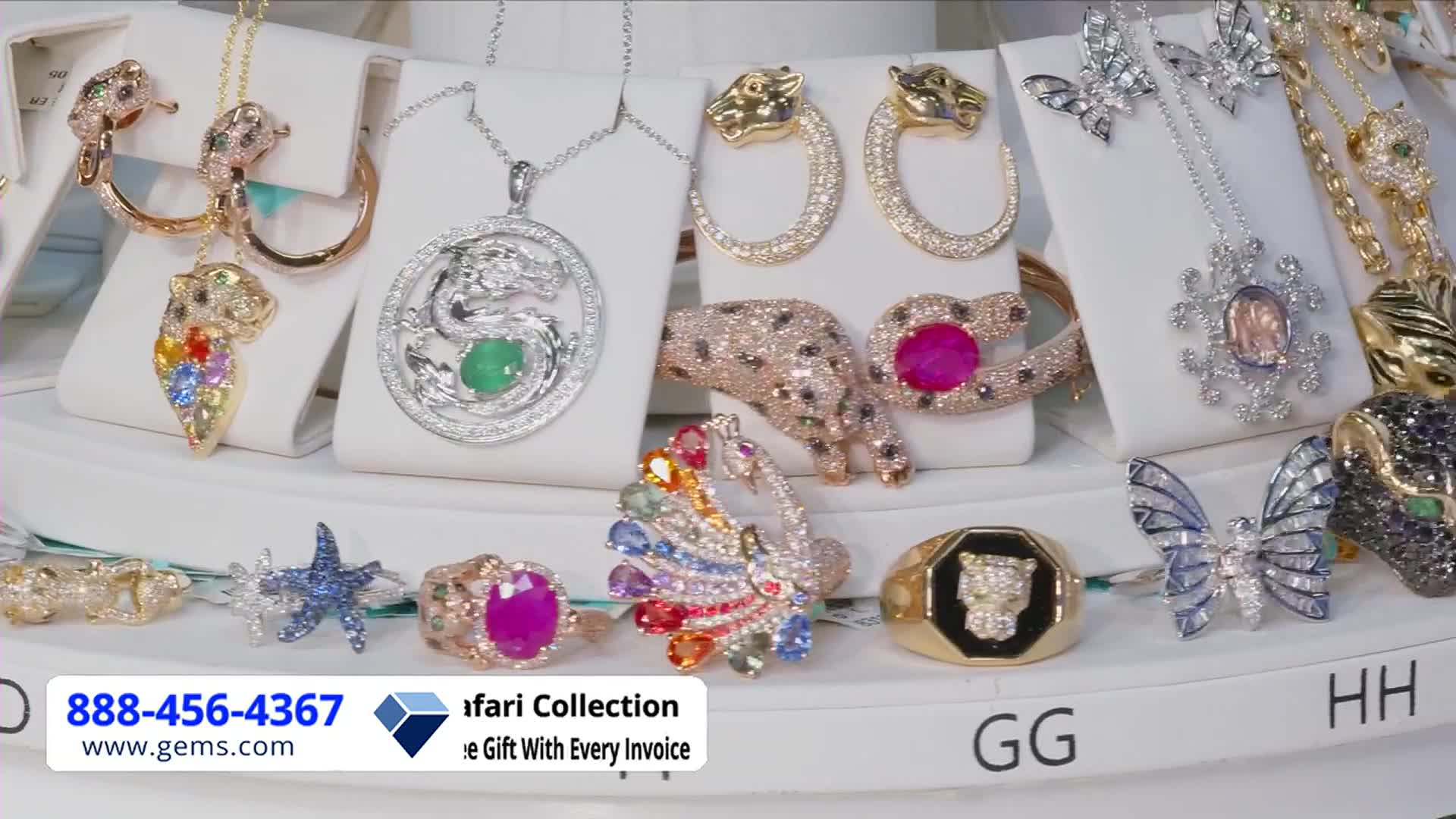 Jewelry, including necklaces and rings, is displayed on white stands, ready for a Gem Shopping Network presentation. A variety of animal-themed pieces, like a jeweled panther bracelet and a dragon pendant, catch the eye.
