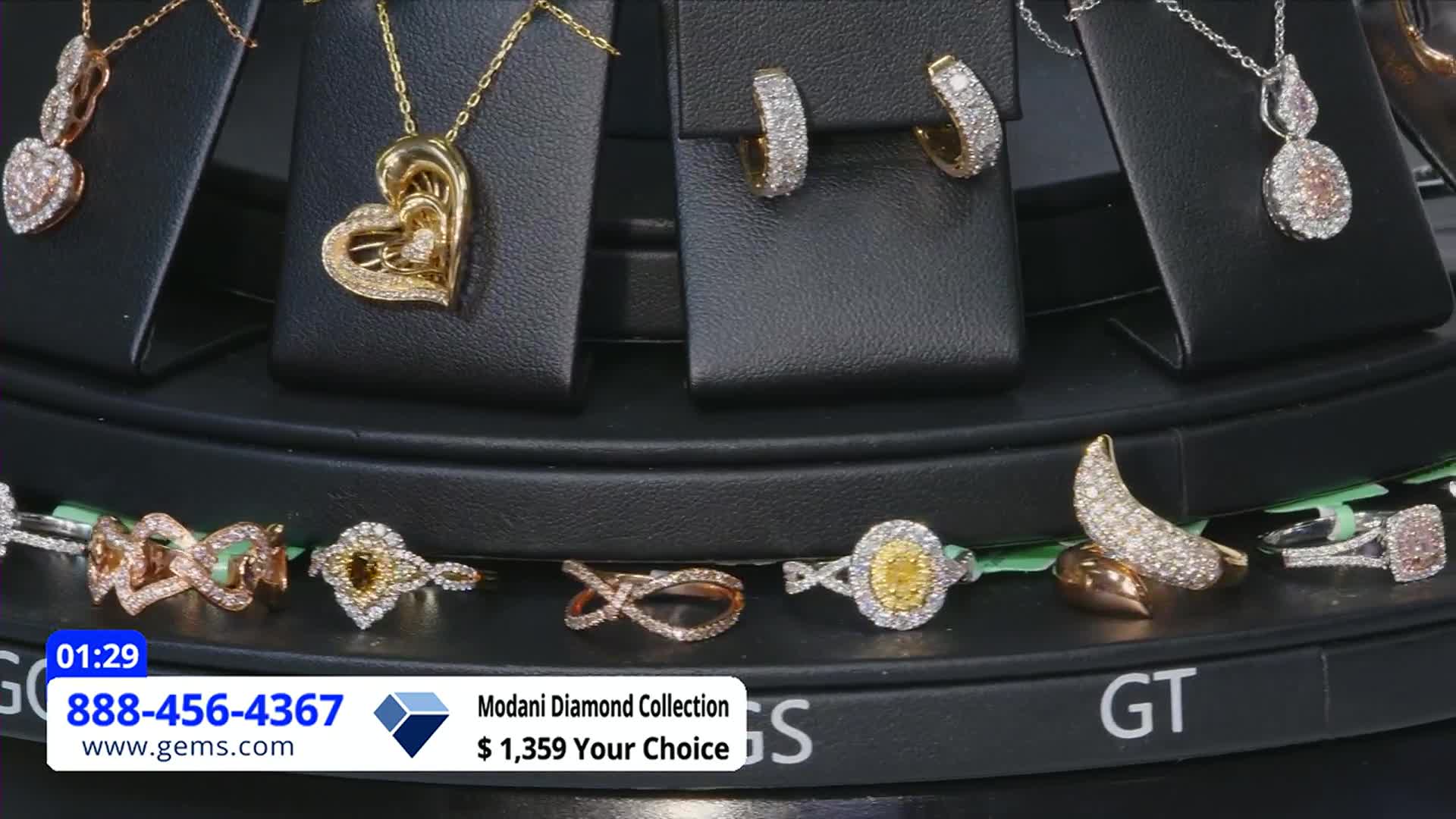 The display rotates, showcasing diamond jewelry in various settings. A lower banner from the Gem Shopping Network advertises the Modani Diamond Collection.
